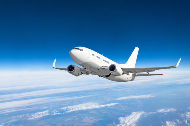 Passenger airplane fly on a hight above clouds and blue sky.
